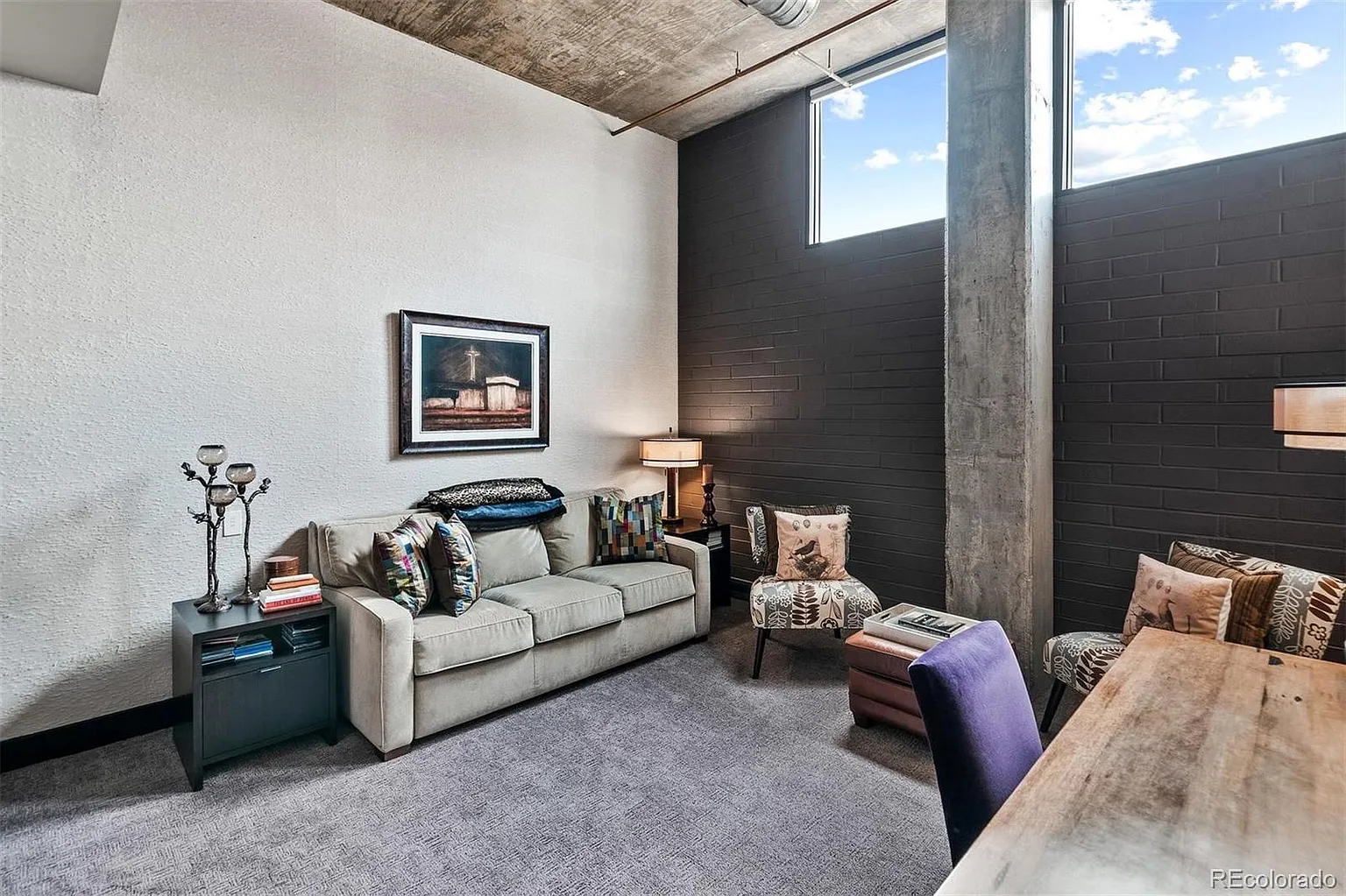 Den with concrete ceiling and painted brick accent wall