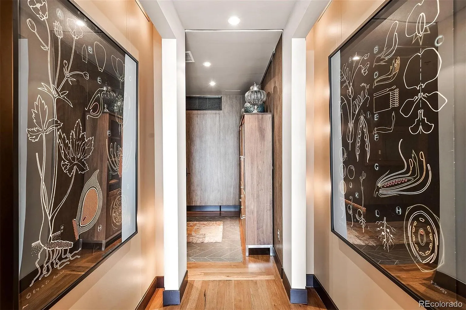 Gallery hallway with framed botanical art and hardwood floors