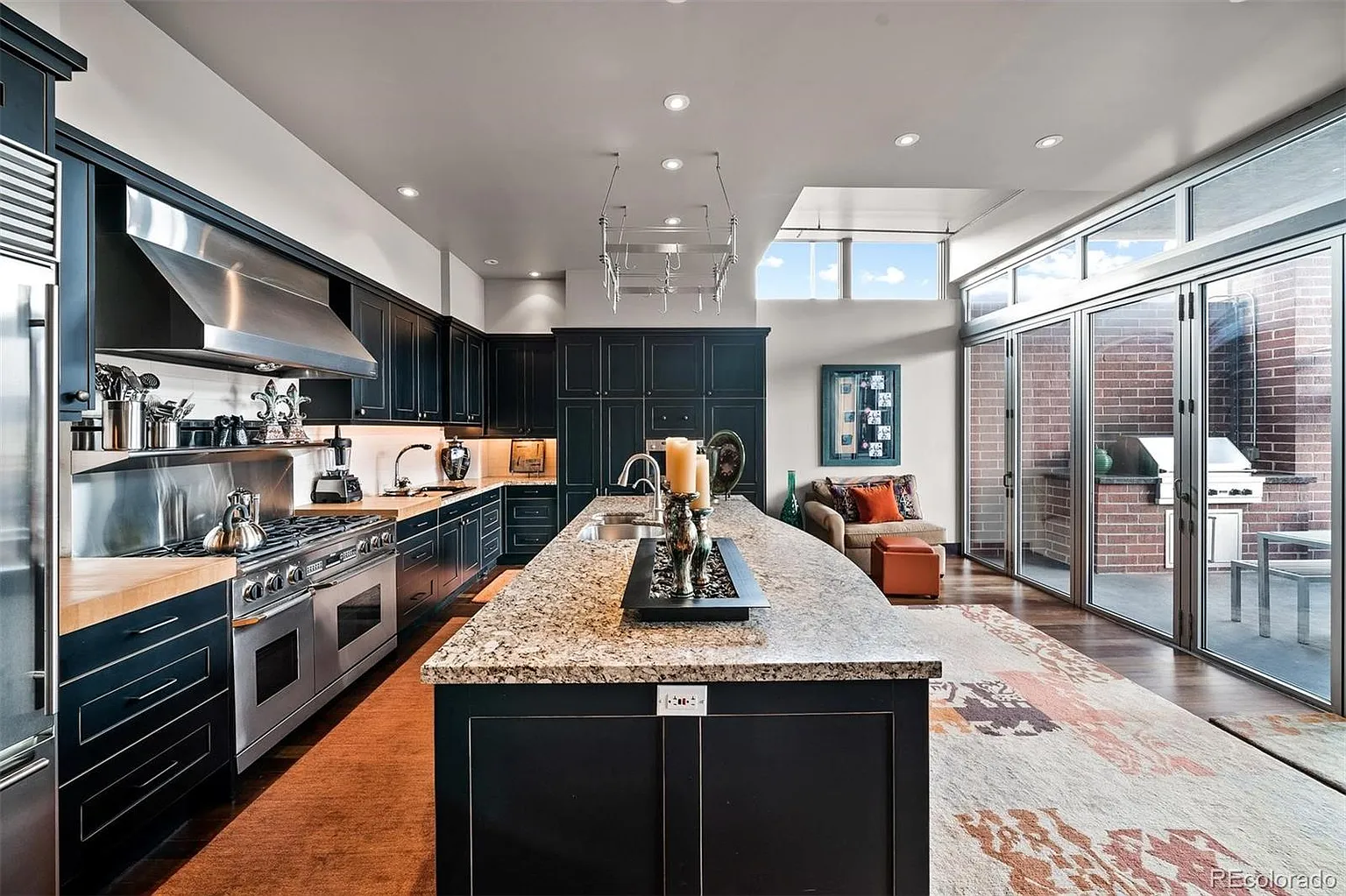 Chef's kitchen with navy cabinetry, granite island, and terrace access