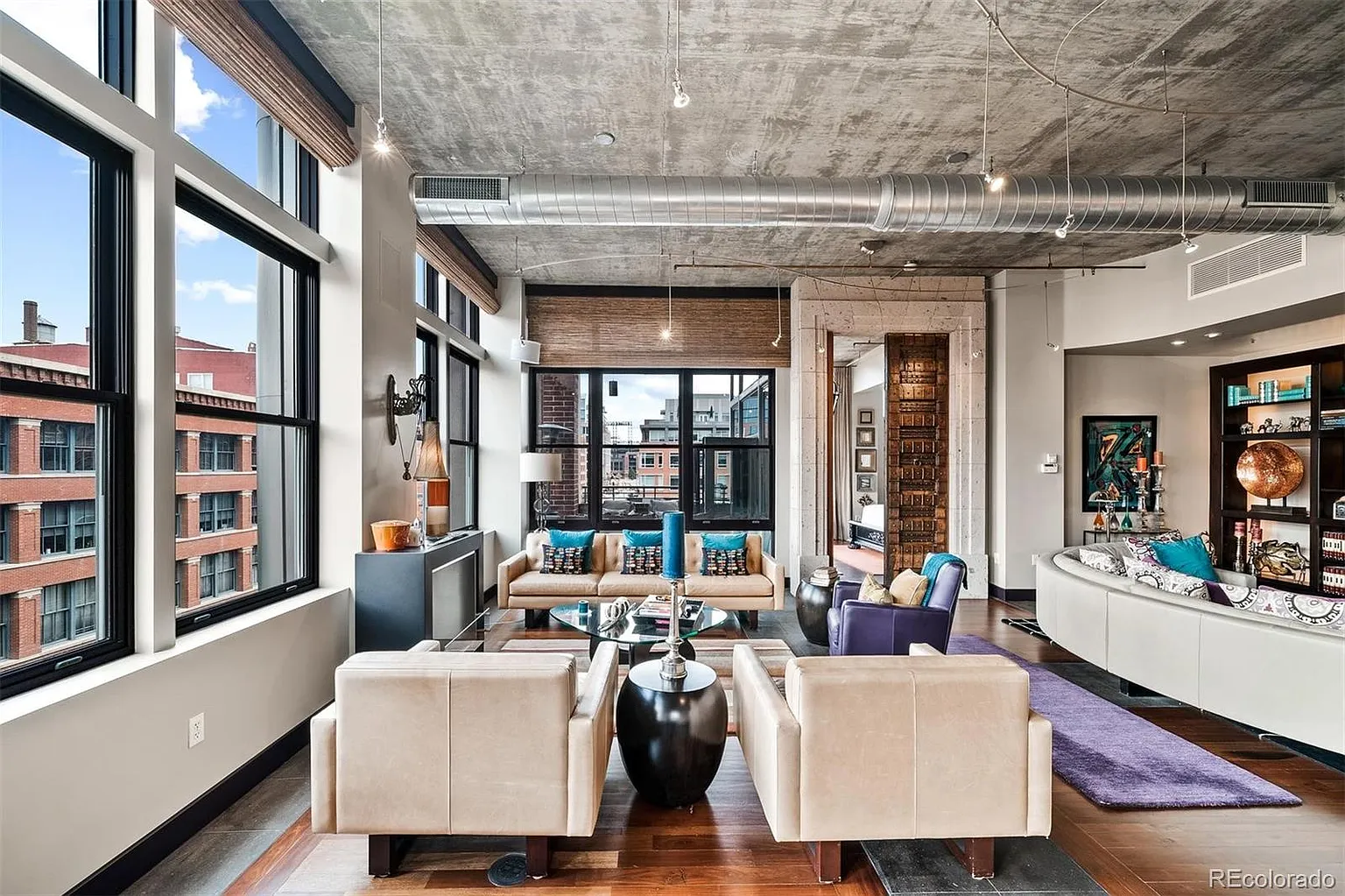 Living area with curved sofa, floor-to-ceiling windows, and downtown views
